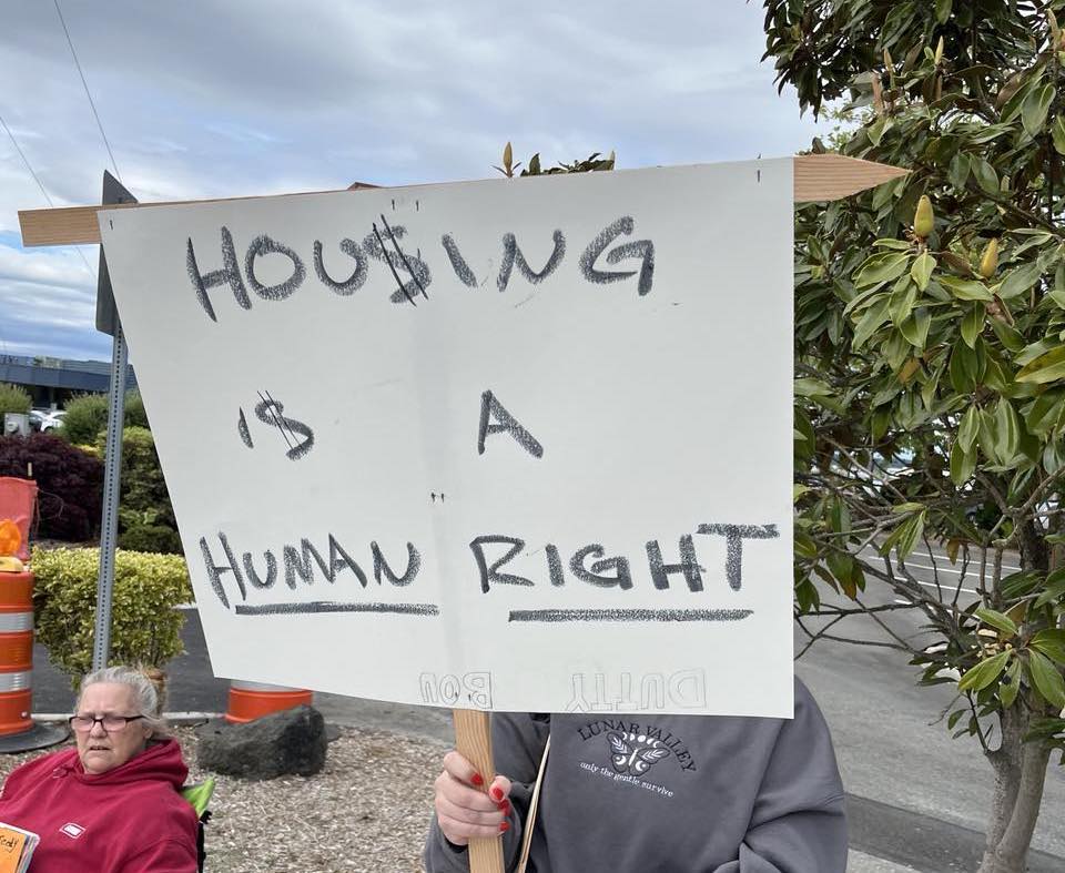 Volunteer holding 'Housing is a Human Right' sign